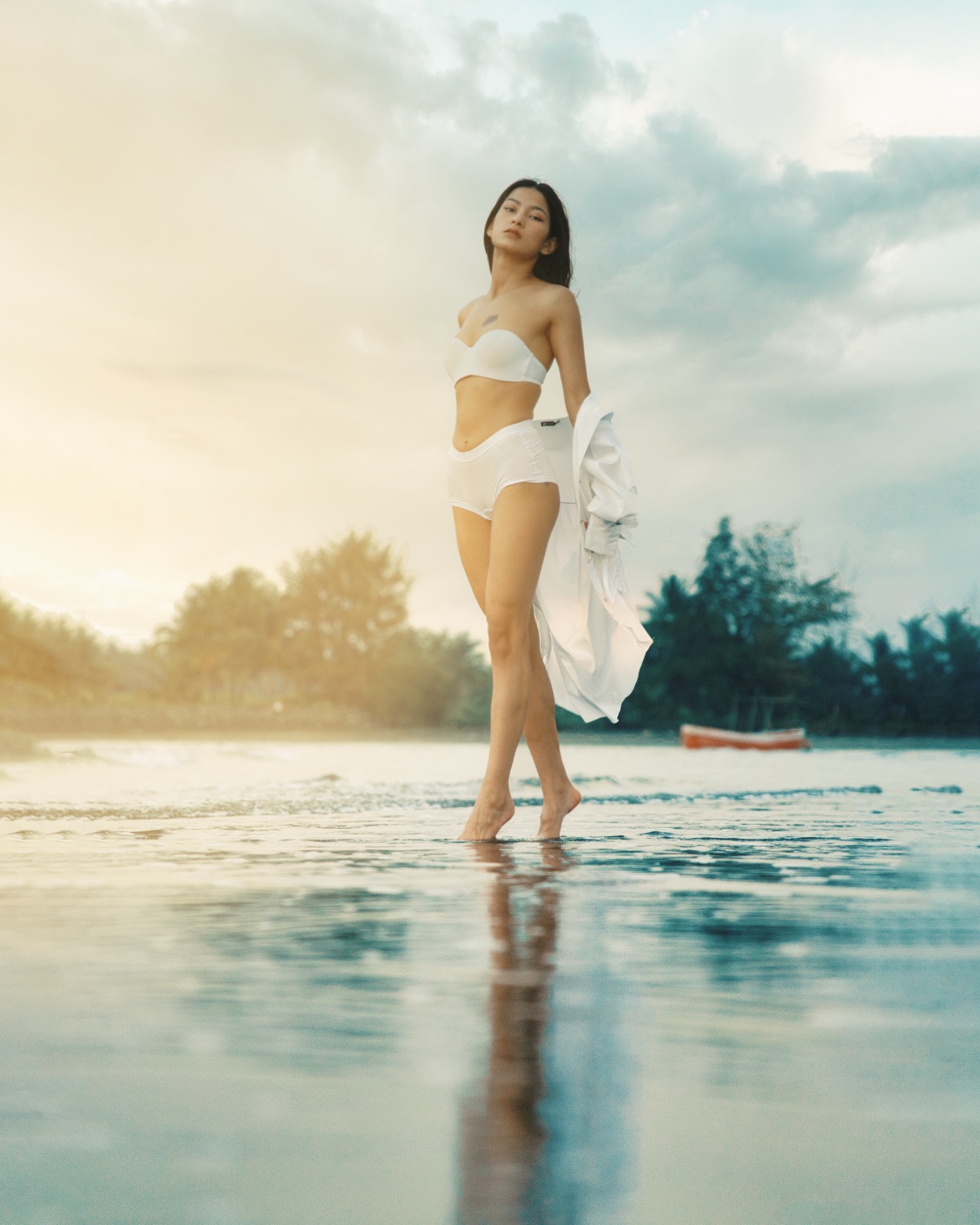 Model in white crossing shallow water at golden hour — La Marée, fashion editorial
